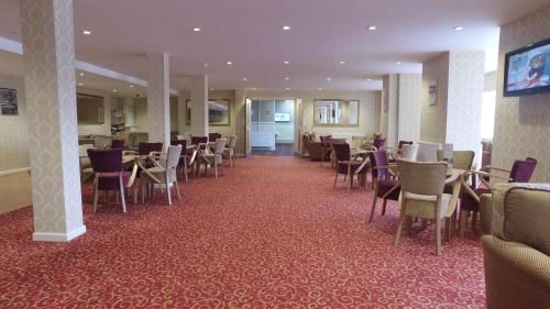 un comedor con mesas y sillas en un hotel en New Beach Hotel, en Great Yarmouth