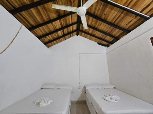 a room with three beds and a ceiling fan at Casa Grande Surf in Guachaca