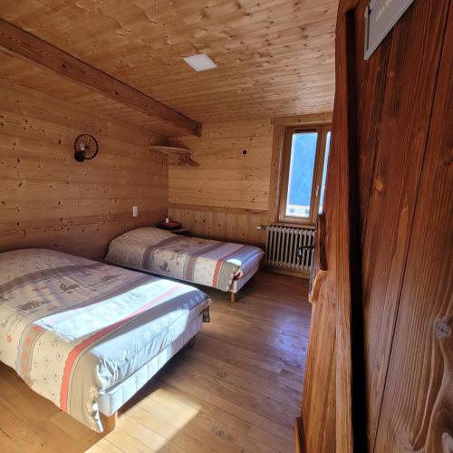 une chambre avec deux lits dans une cabane en rondins dans l'établissement chalet des cyclistes, à La Bresse
