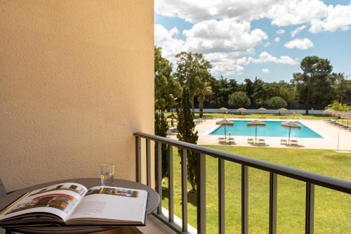 a book on a table on a balcony with a view of a pool at VILA PARK Nature & Business Hotel in Santo André
