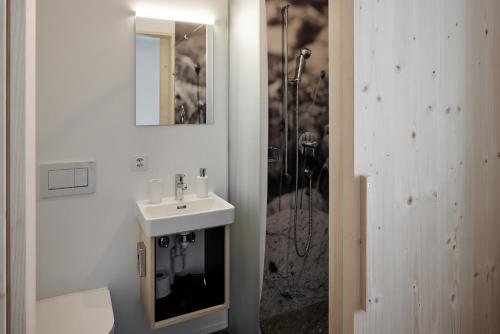 ein weißes Bad mit einem Waschbecken und einer Dusche in der Unterkunft Medelina in Curaglia