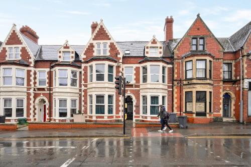 a woman walking in front of a row of houses at Relax in a modern Cardiff home by the City Centre & Bute Park in Cardiff