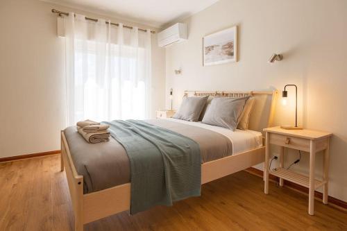 a bedroom with a bed and a table with a lamp at Ericeira Beach Apartment in Ericeira