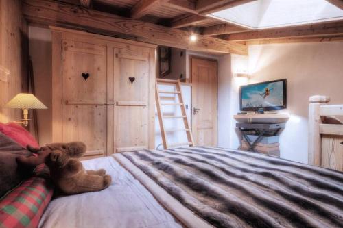 - un ours en peluche assis sur un lit dans une chambre dans l'établissement Duplex Chaleureux au Cœur de Megève 2 p, à Megève