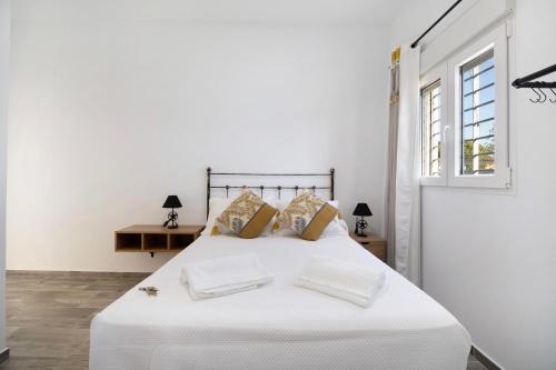 um quarto com uma cama branca com lençóis e almofadas brancos em Villa Magnolia Chiclana em Chiclana de la Frontera