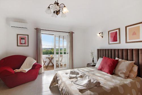 a bedroom with a bed and a chair and a window at Casa Judite in Lagoa