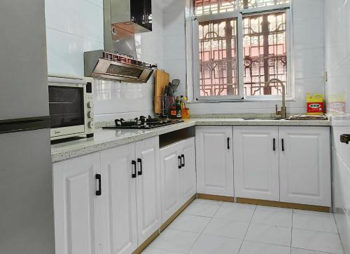 uma cozinha com armários brancos, um lavatório e um micro-ondas em 凤凰古城宝庆民宿 em Fenghuang