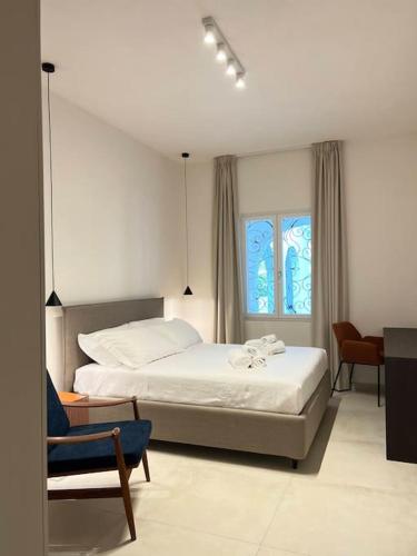 a bedroom with a bed and a chair and a window at Uliveus - Villa Duna fronte mare in Faccia di Trippa