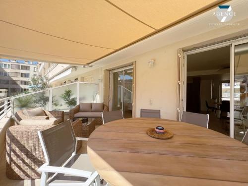 une table et des chaises en bois sur un balcon dans l'établissement Le Suffren, à Sainte-Maxime