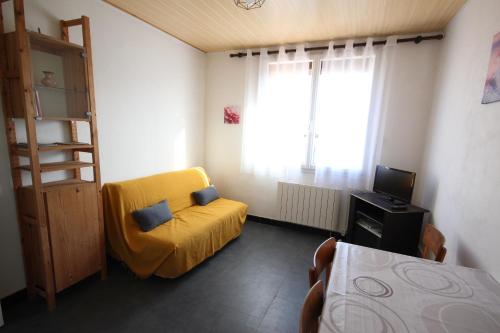 1 dormitorio con silla amarilla y TV en Appartement 2 pièces, au 1er étage pour 2 à 4 couchages, proche commerces et 200m plage de PORTIRAGNES PLAGE LXRH9 en Portiragnes