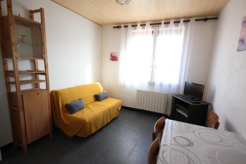 une chambre avec une chaise jaune et une télévision dans l'établissement Appartement 2 pièces, au 1er étage pour 2 à 4 couchages, proche commerces et 200m plage de PORTIRAGNES PLAGE LXRH9, à Portiragnes