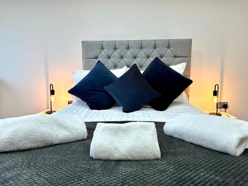a large bed with blue and white pillows on it at York Street Apartments by Blackpool Service Apartments in Blackpool