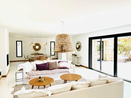 ein Wohnzimmer mit einem weißen Sofa und Tischen in der Unterkunft Villa Grenadier by Intendance Excellency in Cirendinu