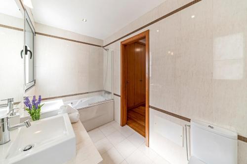 ein Badezimmer mit einem Waschbecken, einer Badewanne und einem WC in der Unterkunft Villa Sol e Mar by Villa Plus in Caniço