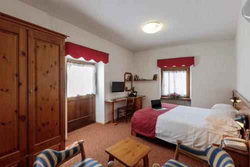 - une chambre avec un lit, un bureau et des chaises dans l'établissement Miramonti Corvara Camera Familiare con bagno, à Corvara in Badia