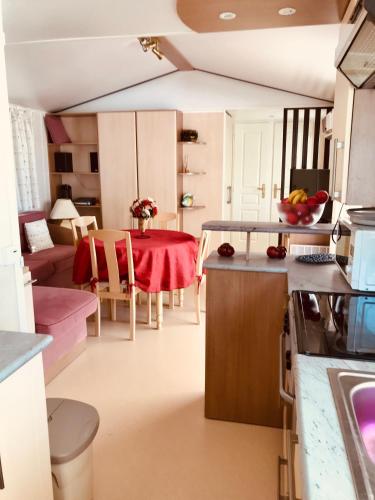 une cuisine et une salle à manger avec une table rouge dans l'établissement MOBIL HOME PLAGE DE PAMPELONNE SUR UN TRES BEL EMPLACEMENT SURPLOMBANT LA BAIE DE PAMPELONNE, à Saint-Tropez
