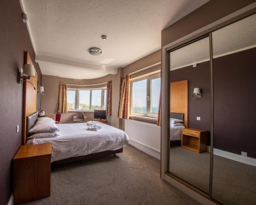 um quarto de hotel com uma cama e um espelho em Shanklin Hotel em Shanklin