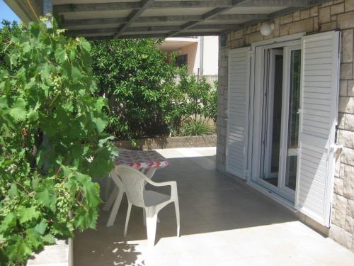 eine Terrasse mit einem weißen Stuhl und einem Tisch in der Unterkunft Apartments Marinko in Stari Grad