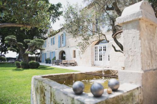 a house with a fountain in front of a yard at Mas d images styled by Scapa Home in Arles