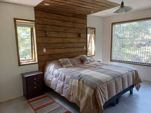 a bedroom with a large bed and two windows at Cabaña Rocario Termas de Chillan in Las Trancas