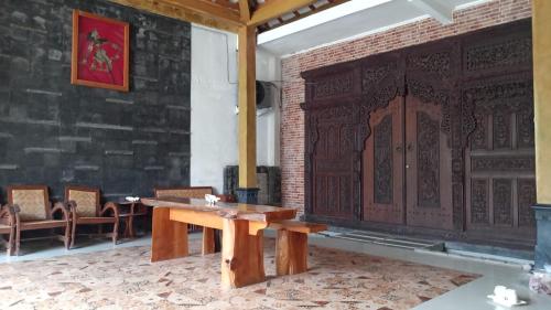 um quarto com uma mesa e cadeiras e uma parede de tijolos em Omah Joglo Pantai Pulau Merah em Pasanggaran
