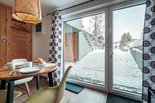 a room with a large window and a table and chairs at Apartamenty Biatlonowe in Kościelisko