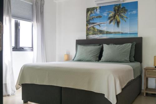 a bedroom with a bed with a palm tree picture on the wall at Blue Bay Resort luxury apartment Palm View in Blue Bay