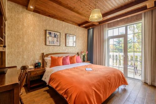 Schlafzimmer mit einem Bett, einem Schreibtisch und einem Fenster in der Unterkunft Qingdao Villa Inn No.12 Seaside (Wusi Suqare) in Qingdao