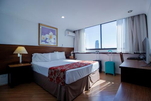 クリチバにあるHotel Dan Inn Curitiba Centroの大きなベッドとデスクが備わるホテルルームです。