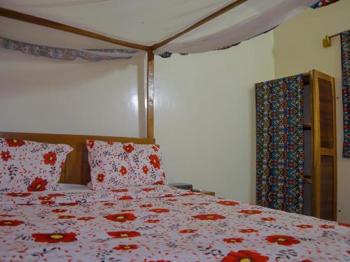 a bedroom with a bed with red flowers on it at La Case a Mamy in Nianing