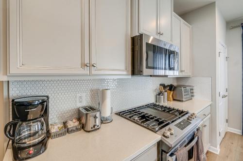 a kitchen with white cabinets and a stove top oven at 30 Mi to Downtown DC Charming Dale City Townhome! in Dale City