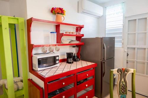 a kitchen with a red cabinet with a microwave and a refrigerator at Studio 1 Tinima with Garden access in Vieques