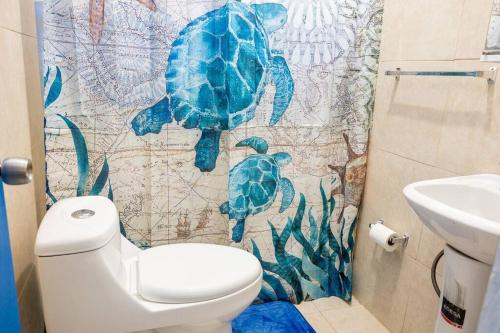a bathroom with a toilet and a turtle shower curtain at Studio 1 Tinima with Garden access in Vieques