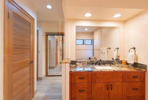 a bathroom with a sink and a large mirror at 1623 Ridge in Kahana