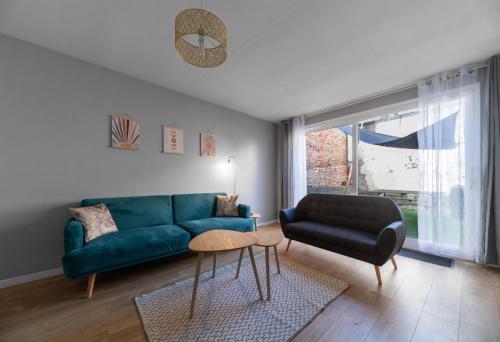 a living room with a blue couch and a table at L'Eugène - Maison 3 chambres in Vichy