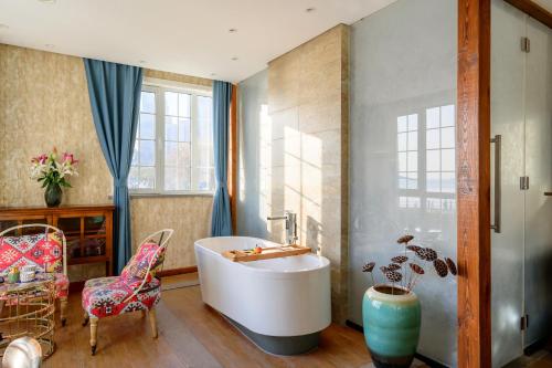 a bathroom with a tub and a chair and a table at Qingdao Villa Inn No.12 Seaside (Wusi Suqare) in Qingdao