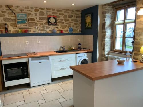 - une cuisine avec des appareils blancs et un mur en pierre dans l'établissement Maison Audierne avec son jardin, à Audierne