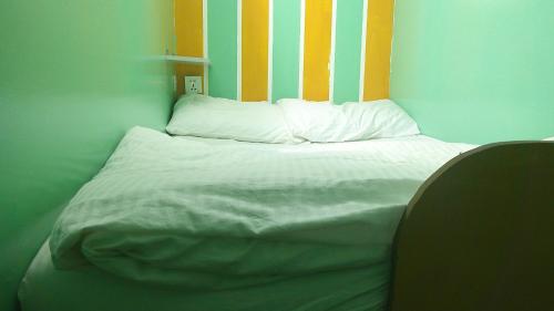 a bed with white sheets and a striped headboard at Ruby Star Hostel Dubai loft Bed Partition G in Dubai