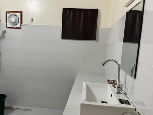 a white bathroom with a sink and a black shower curtain at Palm Path Resort in Jaffna