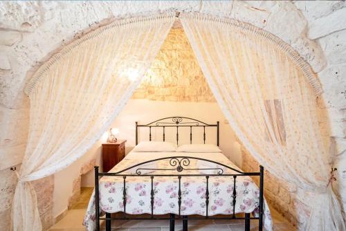 una camera da letto con letto e tende bianche di Trullo Fico a Martina Franca
