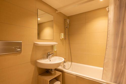 a bathroom with a sink and a shower and a tub at Fred Guest House Hauptbahnhof - Mobile Check-in in Zürich