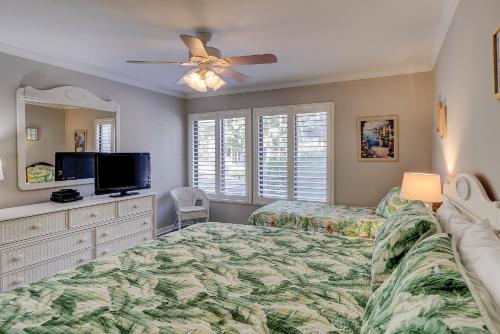 um quarto com uma cama e uma televisão de ecrã plano em Beachwalk 150 em Hilton Head Island