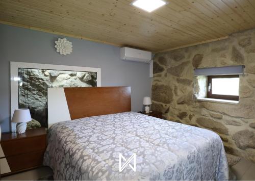 1 dormitorio con cama y pared de piedra en MyStay - O Palheiro, en Caramulo