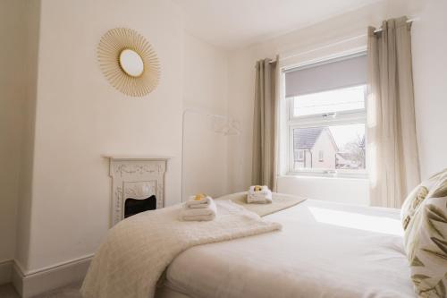 a white bedroom with a bed with towels on it at Lovely 3 bedroom home in Hoole, Chester - Perfect for families in Chester