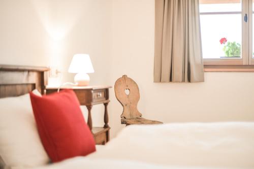 um quarto com uma cama com uma almofada vermelha e uma mesa em Tholer Ferienwohnung 2 em Lagundo