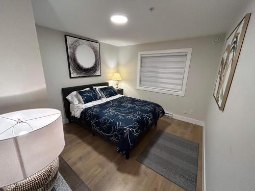 a bedroom with a bed with a blue comforter at New, Spacious 2 Bedrooms in Downtown With Free Parking! in Maple Ridge District Municipality