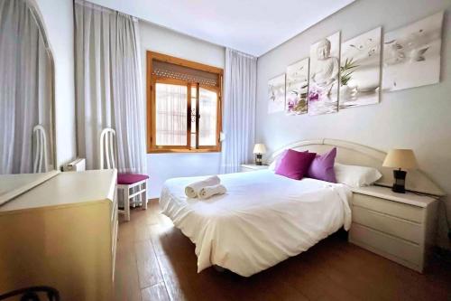ein Schlafzimmer mit einem großen weißen Bett mit lila Kissen in der Unterkunft Tranquilo apartamento cerca del Casco Viejo Bilbao in Bilbao