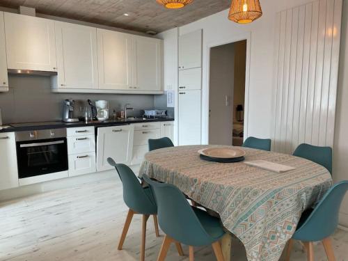 uma cozinha com uma mesa com cadeiras e uma cozinha com armários brancos em LES ILES VUE SUR MER em Agon Coutainville