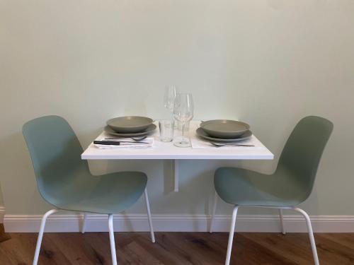 a white table with two chairs and plates and glasses at Monolocale Salvia Self check in in Pavia