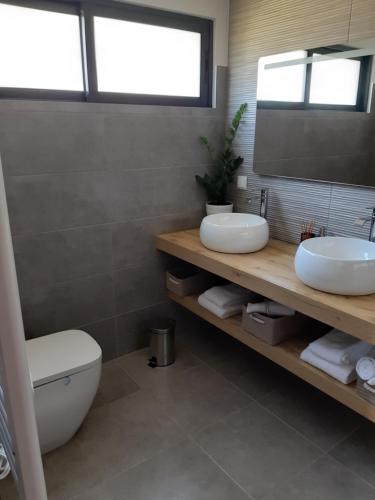 a bathroom with two sinks and a toilet and a mirror at Casa dos Avós in Fajã da Ovelha